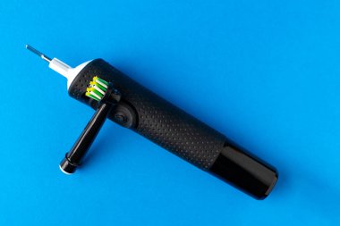 Elektrikli diş fırçası. Mavi arka planda siyah bir diş fırçası, yakın plan..