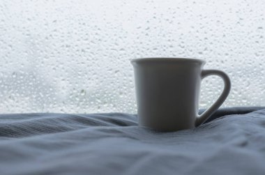 Bir fincan Espresso, yağmurlu bir günde yağmur damlalarıyla yatağa konur. Evde kal konsepti.