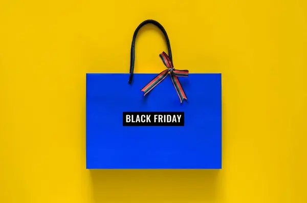 stock image Blue shopping bag with ribbon and word at bag on yellow background for Black Friday shopping sale concept.