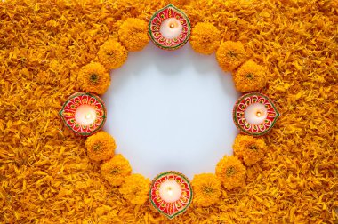 Dekoratif turuncu kadife çiçekleri ve yapraklı rangoli. Diwali festivali için beyaz arka planda kil diya lambası..