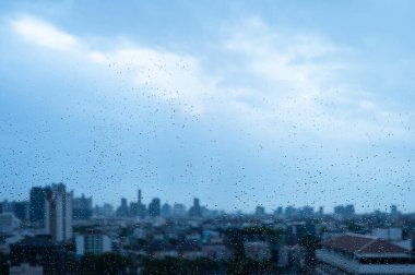 Raindrops on glass with soft city silhouette when monsoon season background.	