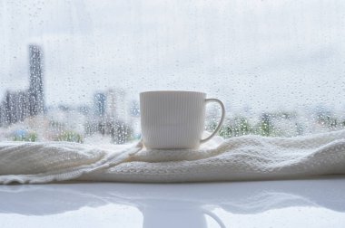 Yağmur pencereye düştüğünde bir fincan kahve eşarpla birlikte masaya konur. Evde kal ve konsepti rahatlat..