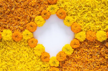 Diwali festivali arka planında sarı ve turuncu renkli kadife çiçekleri ve beyaz alan arka planlı rangoli çiçekleri var..