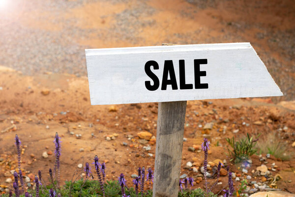 White wooden signpost with the word sale in a glowing light