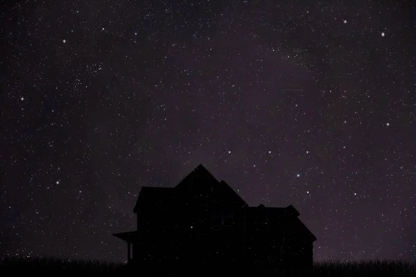 silhouette of a house at night with starry background