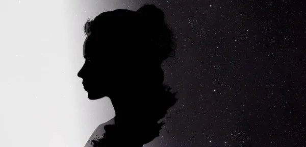 shadow of a woman in profile thinking about a galaxy in her head and in the background universe