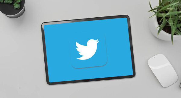 tablet with the twitter logo on the screen on top of a desk