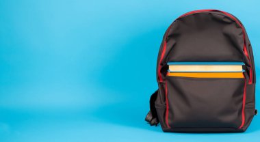 Kırmızı okul çantalı siyah çanta mavi arka planda