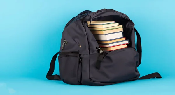 open bag full of school books on blue background