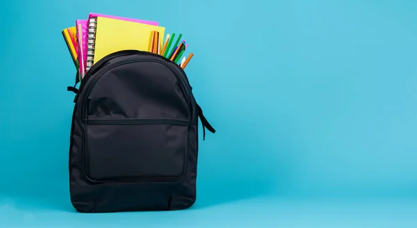 school black bag full of books on blue background HD