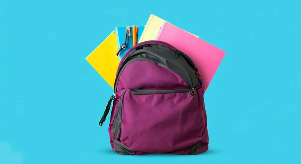 purple school bag full of books on blue background HD