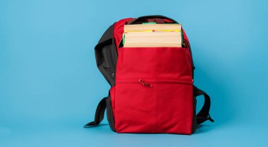 Güzel kırmızı açık okul çantası ve içinde kitaplar var.
