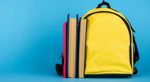 medium yellow school bag with books on blue background