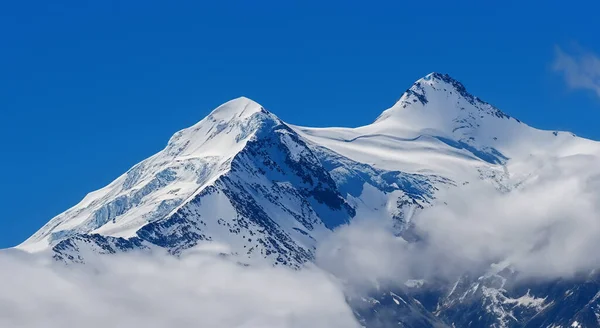 Karla Kaplı Bir Dağın Tepesinin Muhteşem Manzarası Altında Beyaz Bulutlar — Stok fotoğraf