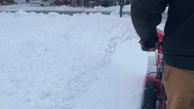 Banliyöde bir kış sahnesinde bir adam gaz gücüyle çalışan bir kar üfleyicisini çalıştırıyor ve evinin önünden taze karı temizliyor. Evler ve buzlu ağaçlarla çevrili kalın beyaz tabakanın içinden geçen yolu temizlerken kar kenarlara fışkırıyor..