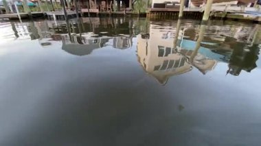 Deniz kıyısındaki bir evin dalgalanan yansımasını yansıtan huzurlu bir yaz teknesi manzarası göl kenarında yaşayan sakin atmosferi yakalıyor..