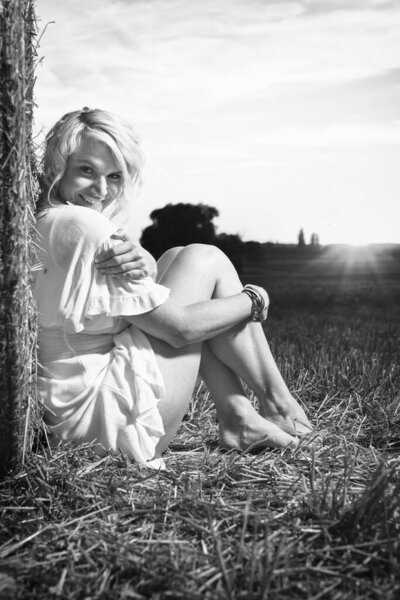 Monochrome portrait of a pretty lady in summer apparel posing on harvested cornfield