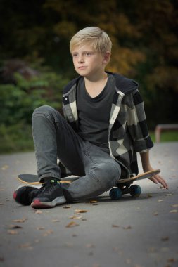 Kaykay parkında poz veren genç bir çocuk.