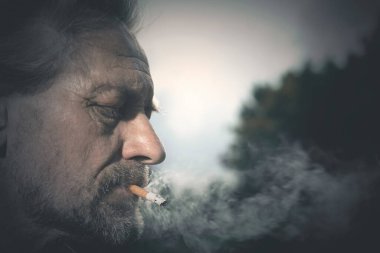 Son zamanlarda şehir parkında sigara içen yaşlı bir adam.