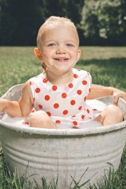 Küçük kız parktaki metal çarşaf küvette banyo yapıyor.