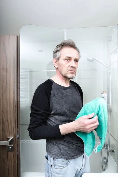 Older man cleaning bathroom space in apartment