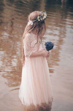 Havuz suyunda lavanta desenli elbiseyle poz veren hoş bir bayan.