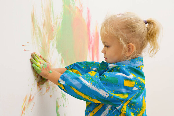 Little blonde girl handpainting clear white house wall