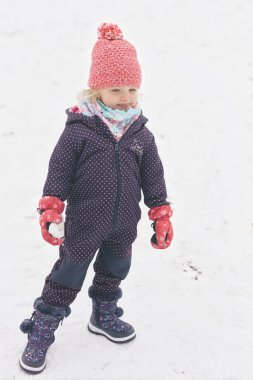 İki yaşındaki kız donmuş şehir parkında kar ve buzun keyfini çıkarıyor.