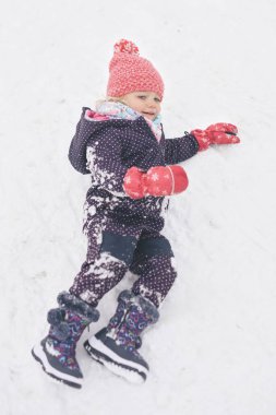 İki yaşındaki kız donmuş şehir parkında kar ve buzun keyfini çıkarıyor.
