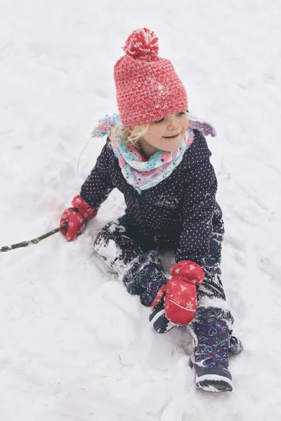 İki yaşındaki kız donmuş şehir parkında kar ve buzun keyfini çıkarıyor.