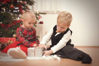 Noel günü birkaç çocuk ağacın yanında hediyelerini açıyor.