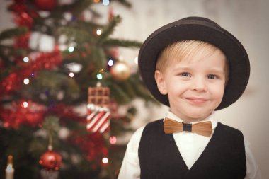 Noel günü melon şapkalı çocuk ağacın yanındaki hediyeleri açıyor.