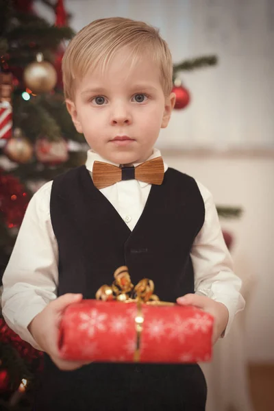 圣诞节期间 身着正式服装的男孩在树旁拆礼物 — 图库照片