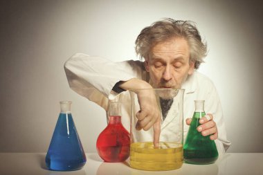 Yaşlı çılgın kimyager bazı sıvılarla bir kimyasal deney hazırlıyor.