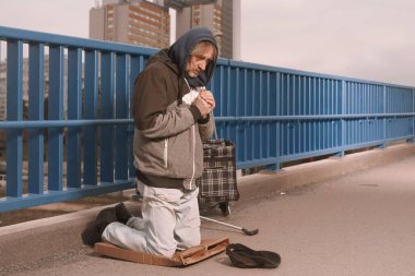 Şehrin üst geçidinde dilenci kıdemli vatandaş biraz para için yalvarıyor.