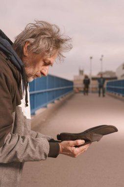 Şehrin üst geçidinde dilenci kıdemli vatandaş biraz para için yalvarıyor.