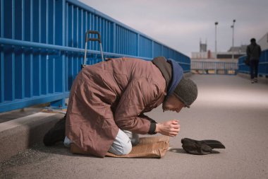 Şehrin üst geçidinde dilenci kıdemli vatandaş biraz para için yalvarıyor.