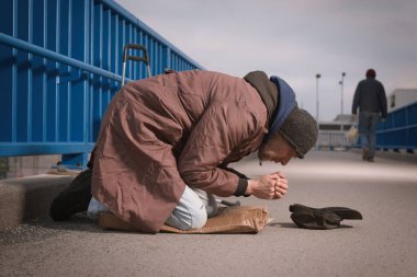Şehrin üst geçidinde dilenci kıdemli vatandaş biraz para için yalvarıyor.