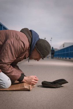 Şehrin üst geçidinde dilenci kıdemli vatandaş biraz para için yalvarıyor.