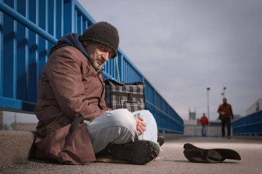 Şehrin üst geçidinde dilenci kıdemli vatandaş biraz para için yalvarıyor.