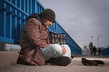 Şehrin üst geçidinde dilenci kıdemli vatandaş biraz para için yalvarıyor.