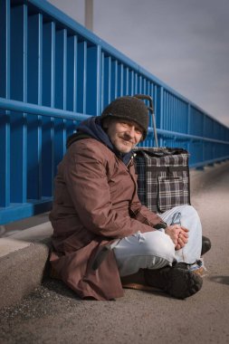 Şehrin üst geçidinde dilenci kıdemli vatandaş biraz para için yalvarıyor.