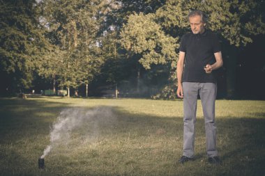 Yaşlı adam dışarıda iki çeşit duman makinesi jeneratörü kullanıyor.