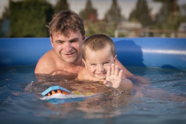 Couple of man and baby cooling during hot day in swimming pool on garden clipart