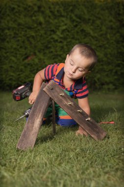 Little boy playing with power and garden tools on garden lawn clipart