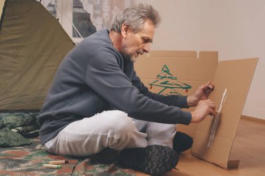 Yaşı büyük bir adam dışarıda kamp yapmak yerine apartman odasında çadır kuruyor.