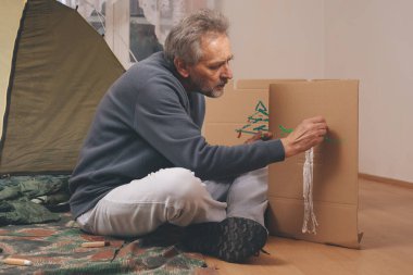 Yaşı büyük bir adam dışarıda kamp yapmak yerine apartman odasında çadır kuruyor.