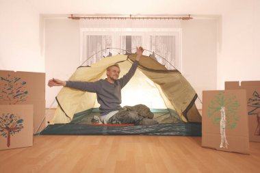 Yaşı büyük bir adam dışarıda kamp yapmak yerine apartman odasında çadır kuruyor.