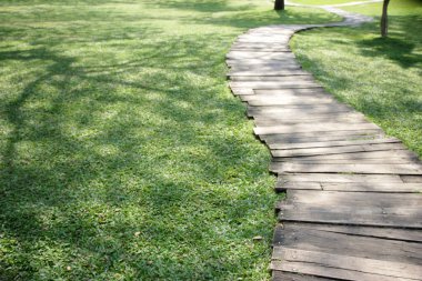 Bahçede doğal arka planı olan bir sıra ahşap yol.
