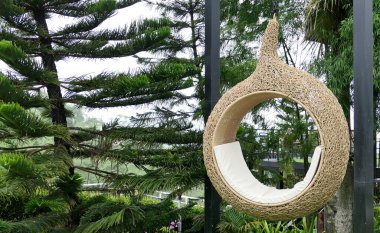 Kafeye asılmış bir koza şeklinde hasır bir koltuk.